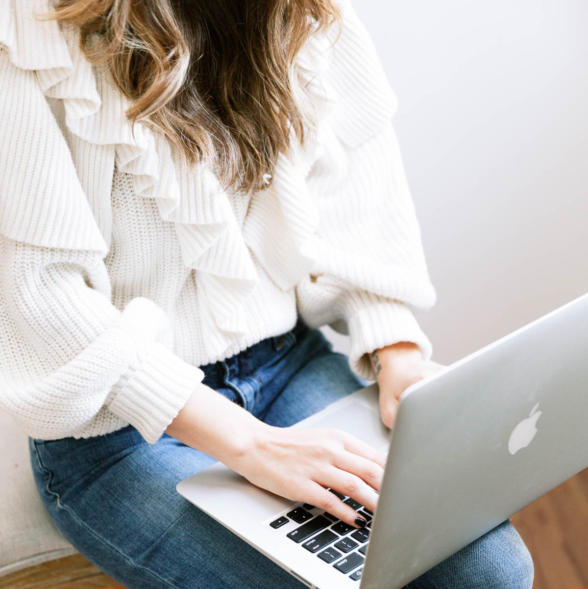 En kvinnlig egenföretagare som sitter med sin laptop i knäet och arbetar med sin SEO-strategi