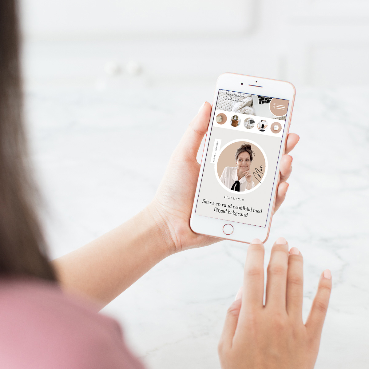 En kvinna som tittar på en mobilskärm där det visas en rund profilbild med rosa bakgrund